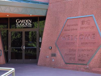 The image shows the entrance to a building with a large glass door and a distinctive hexagonal stone sign on the wall to the right.