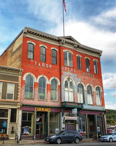 A red brick Italianate-style building with "TABOR OPERA HOUSE" painted in large white letters on the facade, featuring arched windows, a balcony, and storefronts at street level including "FURMAN'S".
