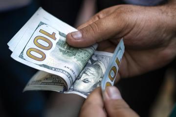 Hands counting US one-hundred-dollar bills