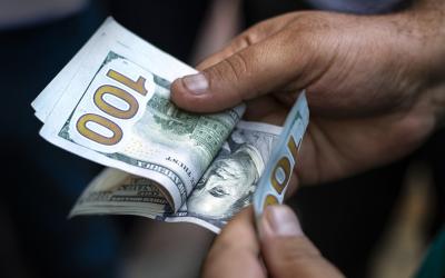 Hands counting US one-hundred-dollar bills