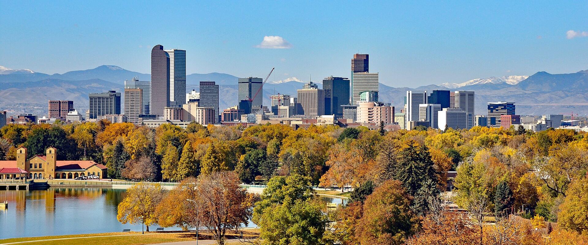 Downtown Denver skyline with the Rocky Mountains behind, seen across a lake in City Park in autumn