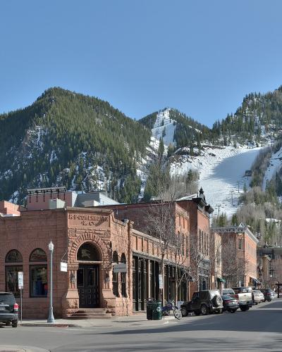 Downtown Aspen's brick storefronts beneath Aspen Mountain's ski runs